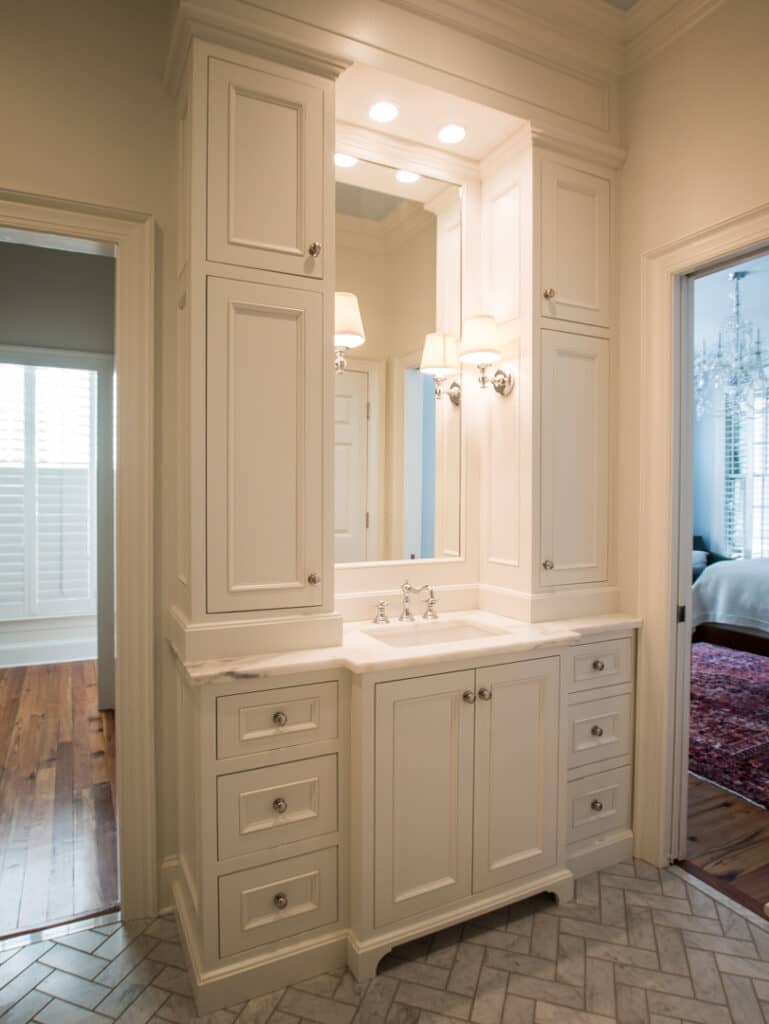 White bathroom vanity with a sink and mirror bordered by custom cabinets.