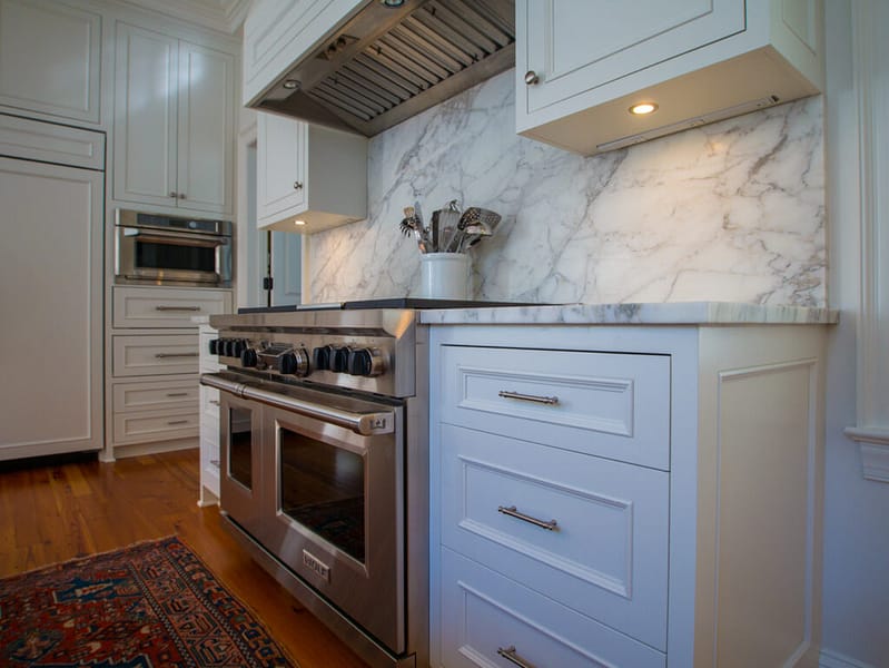 White kitchen cabinets with marble backsplash and countertops.