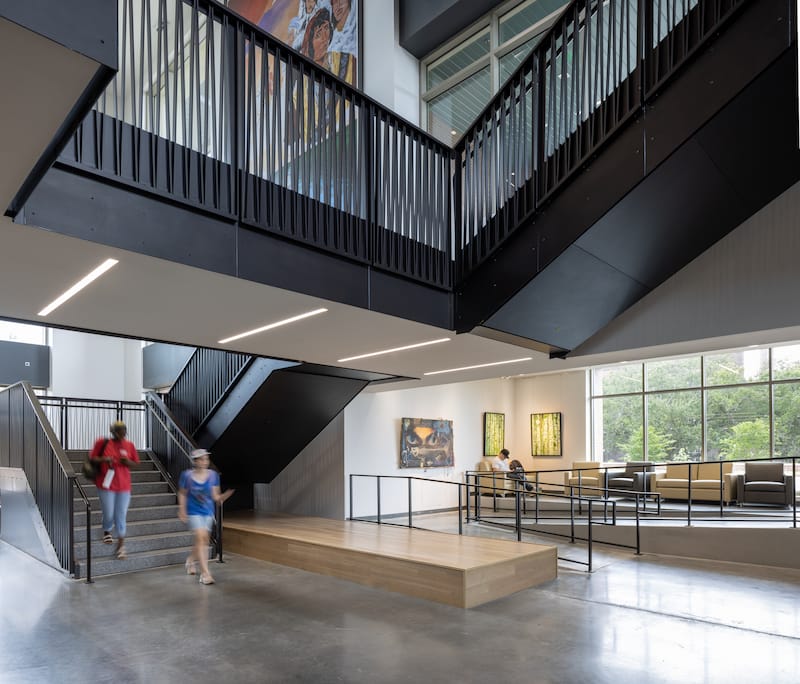 One of the levels of the FSU Student Union has an accessible ramp leading up to a seating area with framed artwork on the walls. A wide staircase leads to another level with more artwork.